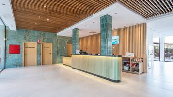 A modern reception area with a wooden ceiling, a reception desk, and a wall-mounted TV.