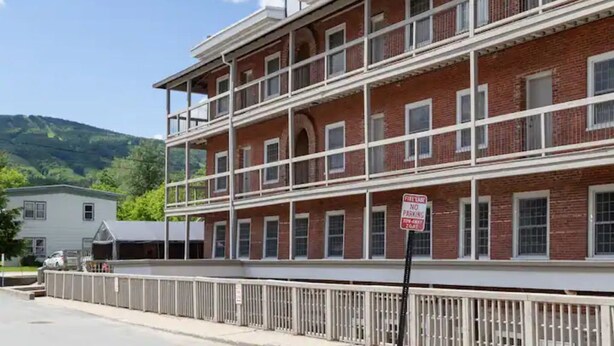 A multi-story brick building with a white railing in front.