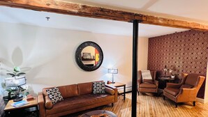Ein gemütliches Wohnzimmer mit einem braunen Ledersofa, einem runden Couchtisch und einer Wand mit Muster.