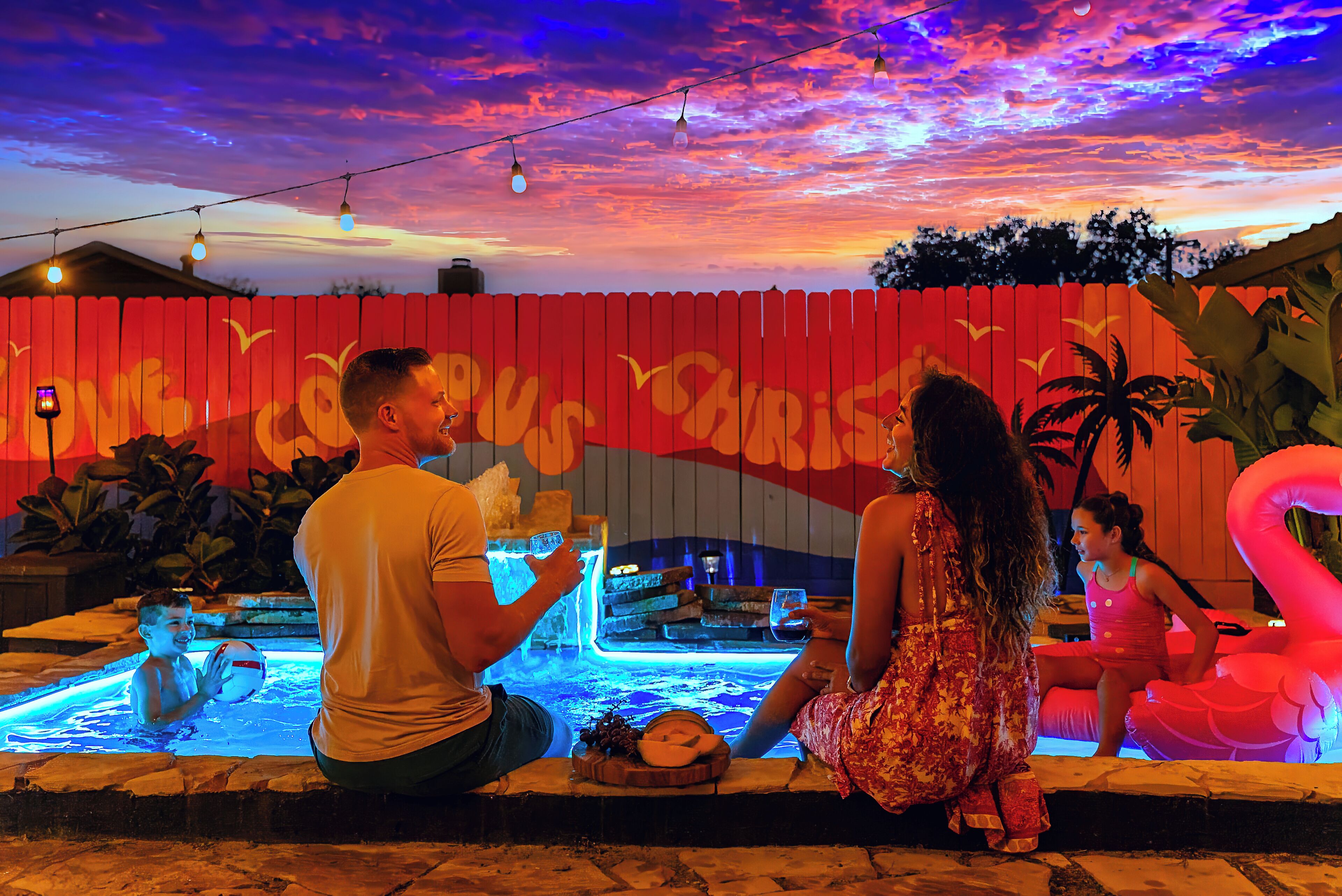Un espace piscine agrémenté d’une clôture rouge, d’un jacuzzi et d’un flotteur en forme de flamant rose.