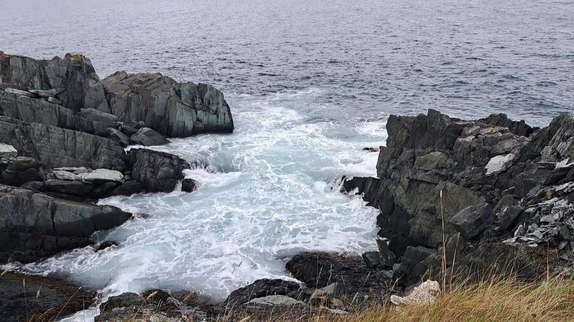 Une côte rocheuse où les vagues déchaînées de la mer s'écrasent contre les rochers.