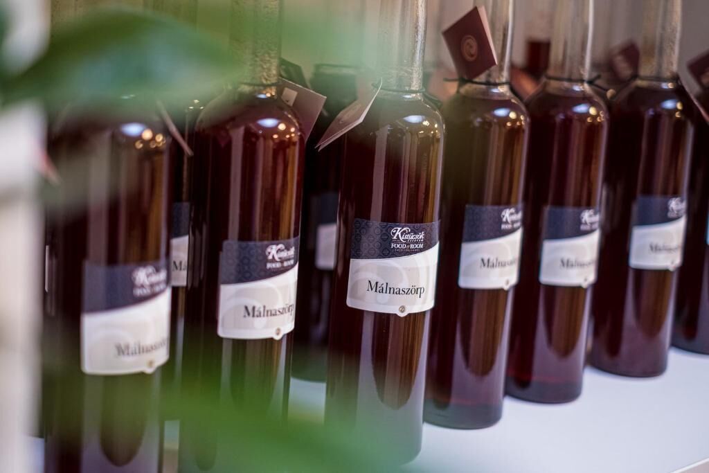 Várias garrafas de vinho com etiquetas, algumas com penduricalhos, dispostas numa estante.