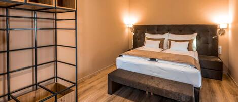 A bedroom with a bed, bedside tables, a bench, and a shelving unit.