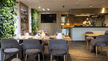A modern restaurant with a wooden interior, a bar area, and a chef preparing food.