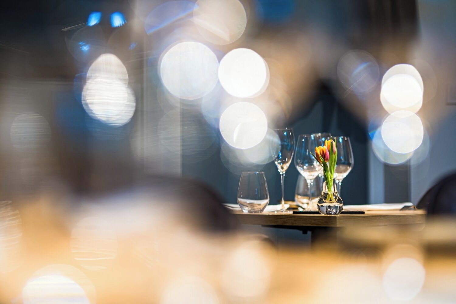 Une table à manger ornée d’un vase de tulipes et de verres à vin.