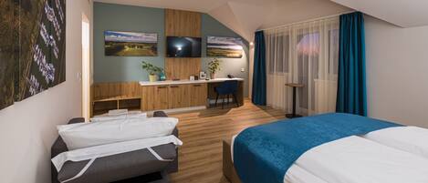 A modern hotel room with a bed, a sofa, a desk, and a TV.