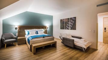 A modern bedroom with a large bed, a bedside table, a chair, and a sofa.