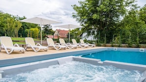 A swimming pool with lounge chairs and umbrellas, surrounded by trees and a house in the background. - Kistücsök Food & Room (Balatonszemes)