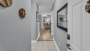 A hallway with a wooden floor, a door with a brass handle, and a mirror on the wall. - Elegant 3-bedroom condo with 2 King beds/2 twins close to OWA/Foley Sports Plex. (Foley)