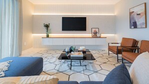 A modern living room with a sofa, a coffee table, and a TV mounted on the wall. - Francheska`s Villa: Private Pool/Spa, 24/7 Support (Davenport)