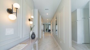 A hallway with a marble floor, a bench, wall sconces, and a vase with plants. - Francheska`s Villa: Private Pool/Spa, 24/7 Support (Davenport)