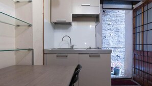 A compact kitchen with a sink, cabinets, and a dining area with a table and chair. - Schöne, Kleine Wohnung in Zentraler Lage (Siena)