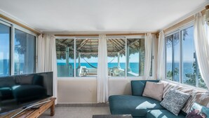 A living room with a large TV, a sofa, and a view of the sea through large windows. - Casa Mañana (La Ventana)