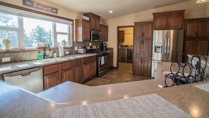 A spacious kitchen with wooden cabinets, a stainless steel refrigerator, and a built-in oven. - 24 Quiver Circle · Spectacular Mountain View ★ 5 Acres ★ PIKES PEAK (Florissant)