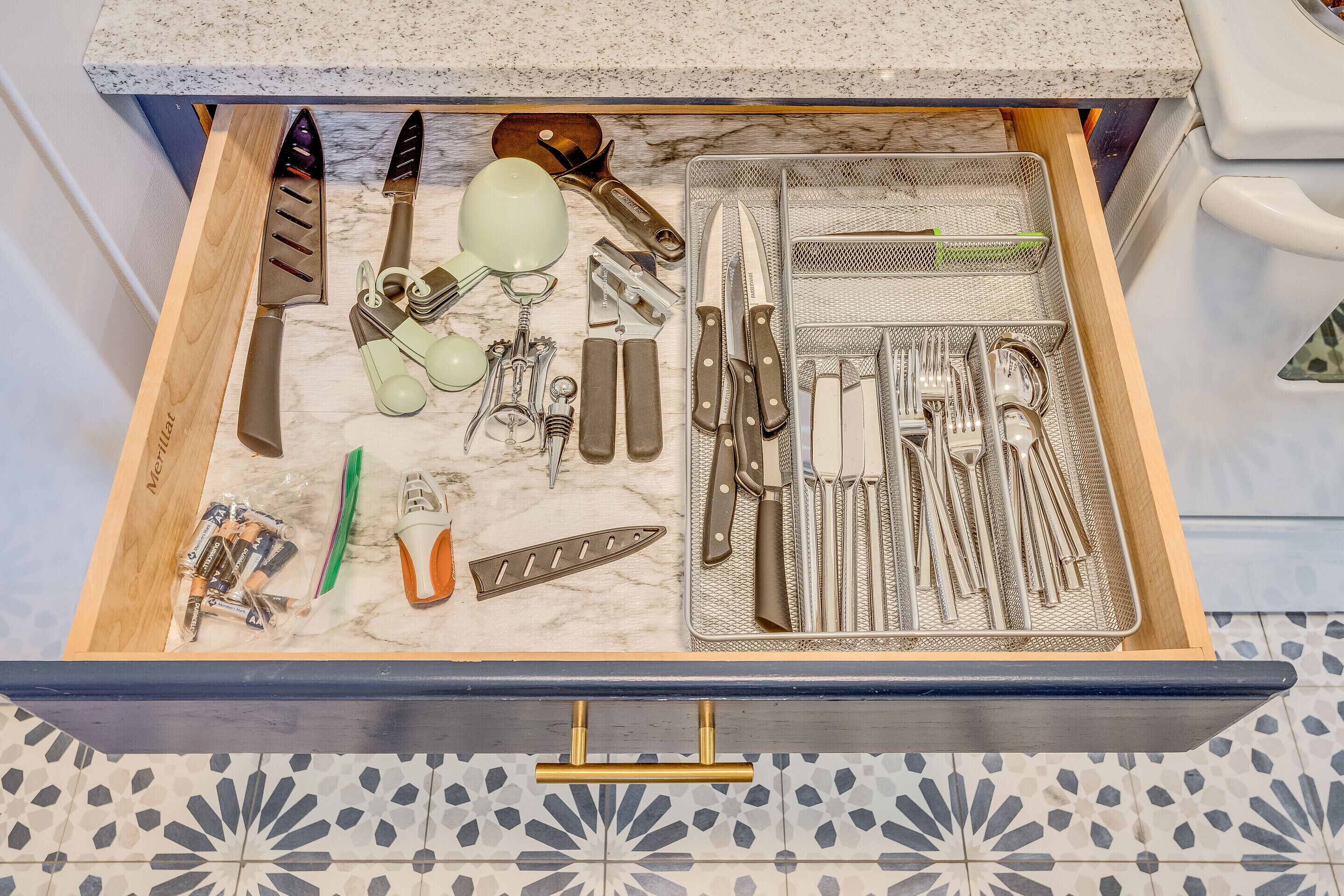 Un tiroir de cuisine contenant divers ustensiles et outils de cuisine, rangés de manière ordonnée.