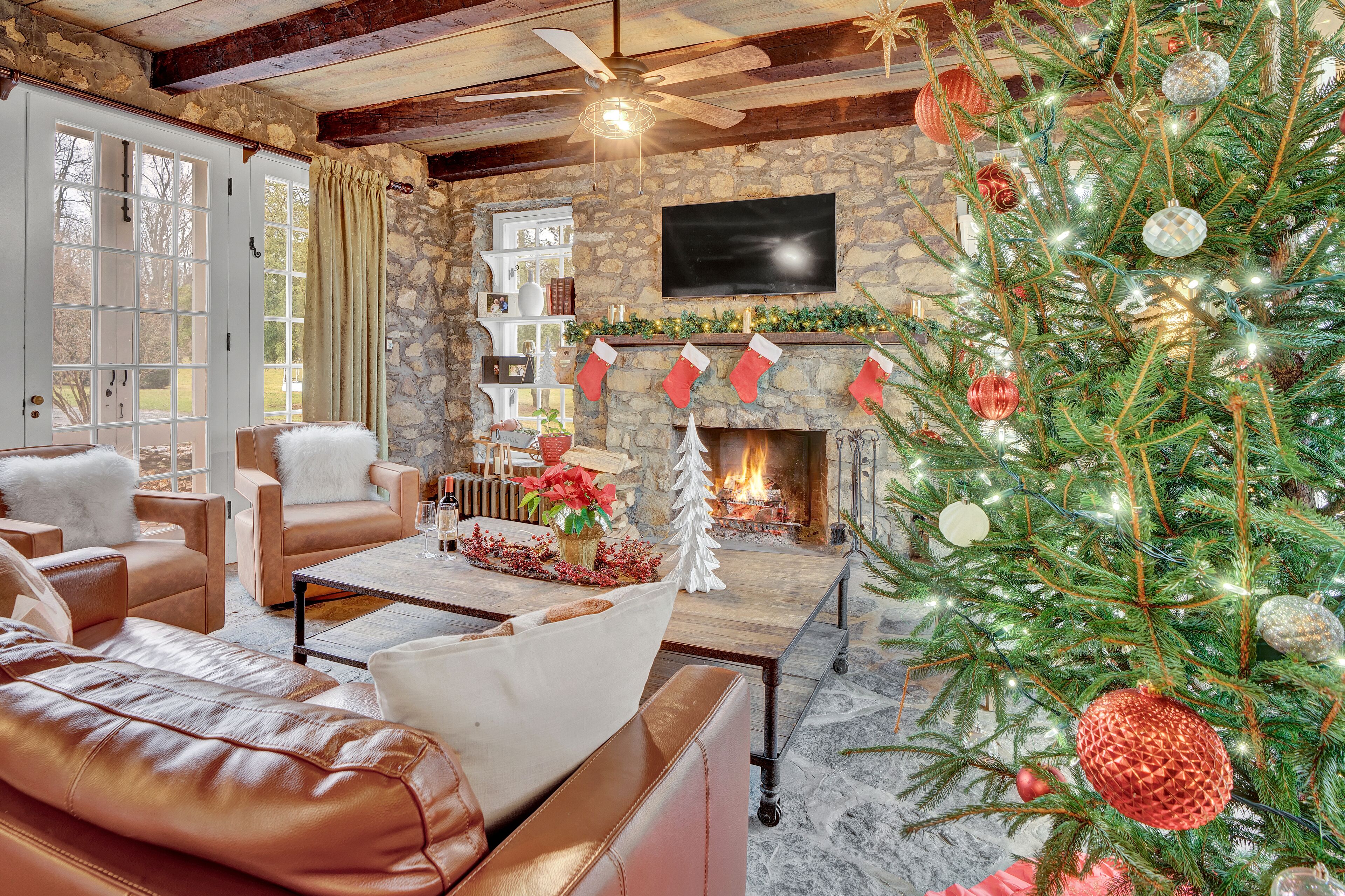 A cozy living room with leather sofas, a fireplace, and a Christmas tree.