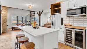 A modern kitchen with a central island, built-in ovens, and a large window.