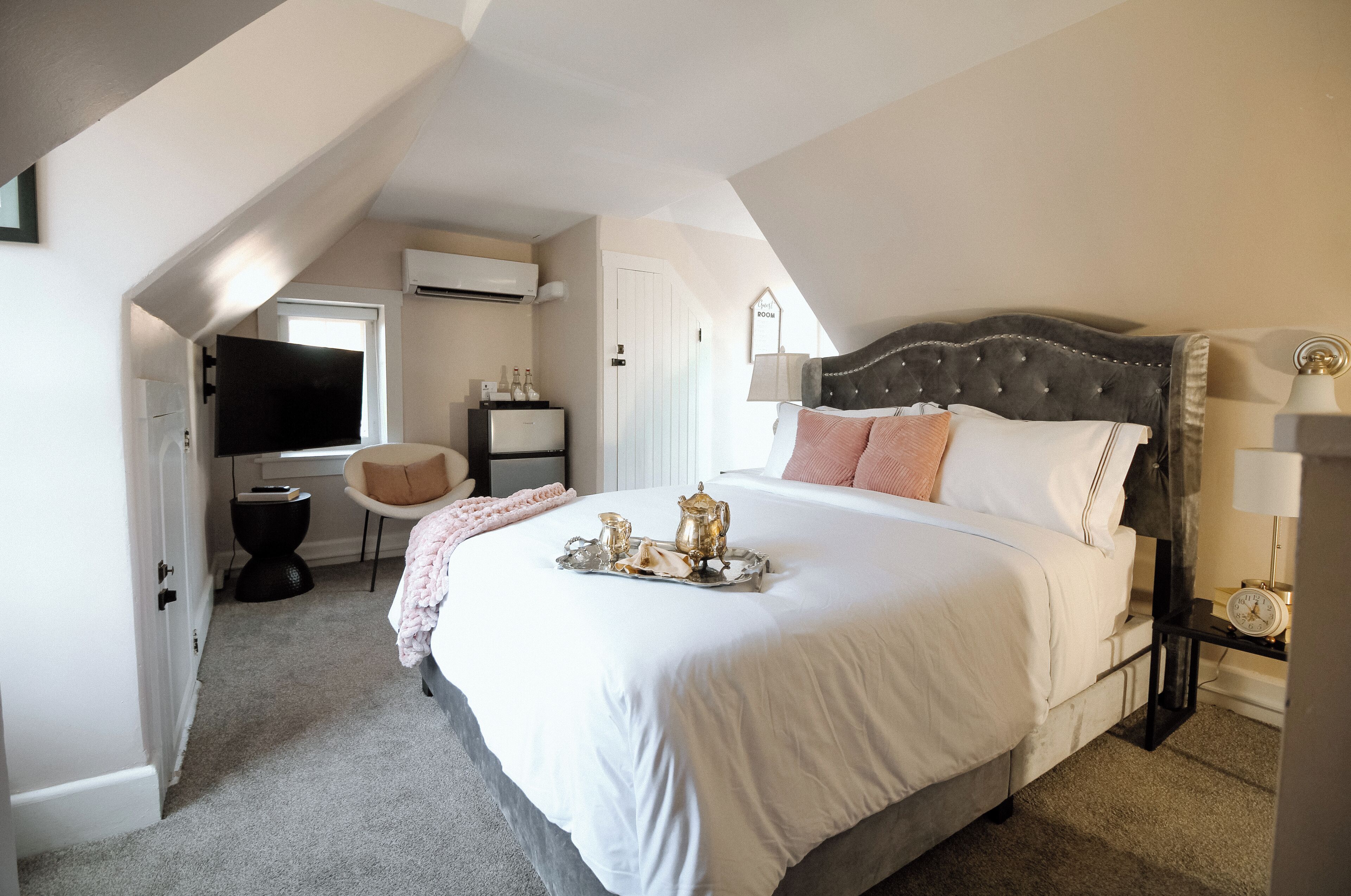 A bedroom with a large bed, a TV, a desk, and a chair.