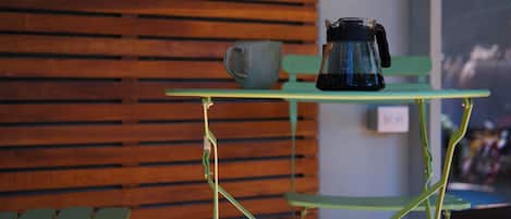 A green metal table with a coffee maker and a mug on top.