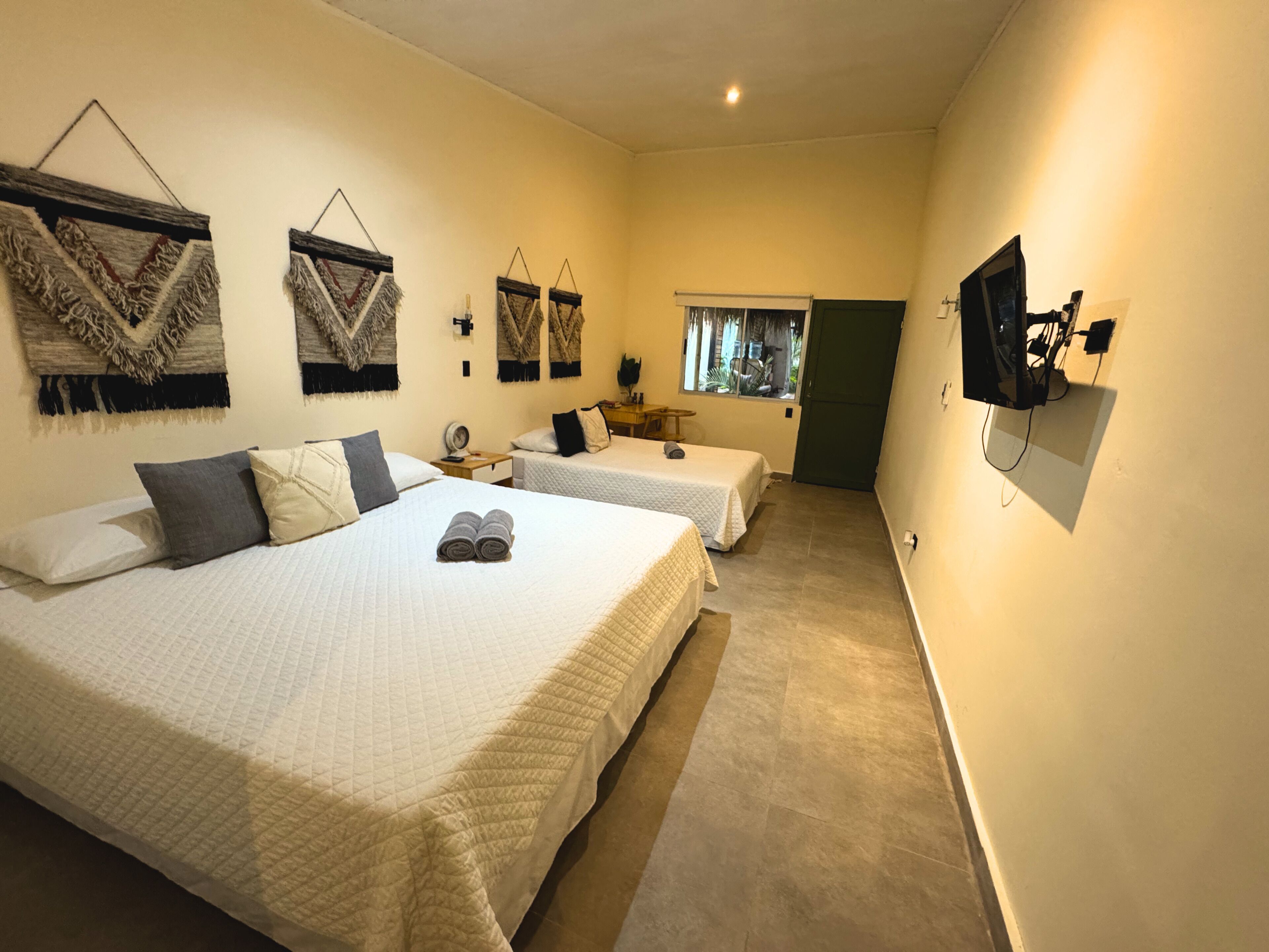 A hotel room with two beds, a TV, a window, and wall-mounted decor.