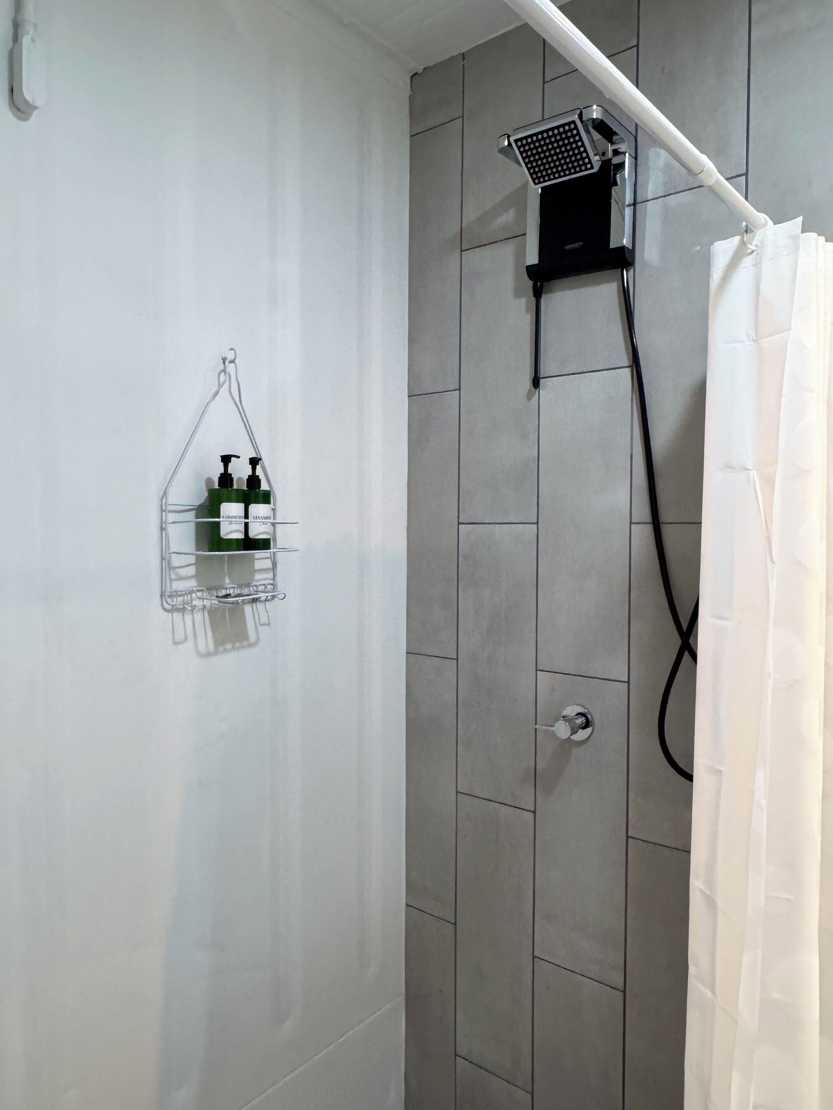 Ducha con cabezal de ducha de mano y cortina blanca.