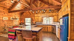 A log cabin interior with a central island, wooden cabinets, and a blue refrigerator. - 1 Mi to Rainbow Lake: Lakeside Cabin w/ Deck! (Lakeside)