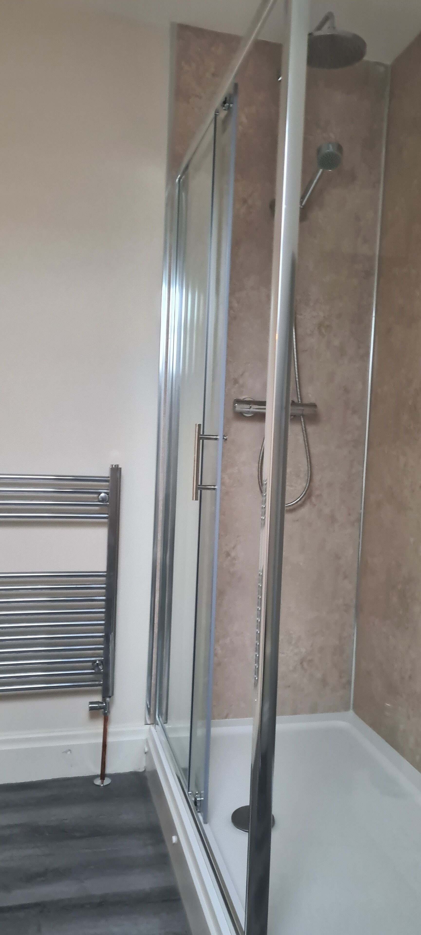 Un baño con ducha de vidrio, toallero y bañera.