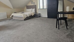 Ein Schlafzimmer mit Bett, Schreibtisch, Stuhl und Heizkörper.