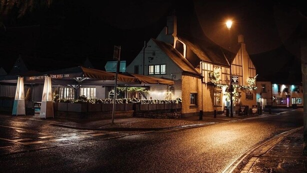 Ein traditionelles Gebäude mit einem Schild, auf dem 'Welcome to The Olde Bull Inn' steht, bei Nacht.