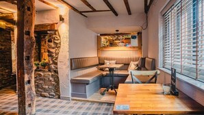 A cozy corner with a wooden table, a cushioned bench, and a stone wall. - 1 Bed Flat - Sleeps 2 - Parking - Wifi (Newport)