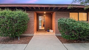 Une maison moderne en briques, dotée d’une entrée accueillante, d’un porche abrité et d’un aménagement paysager bien entretenu.