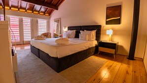 A bedroom with a large bed, wooden flooring, a nightstand with a lamp, and a painting on the wall. - Quinta da Corredoura Hotel Rural (Guimarães)