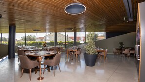 A spacious dining area with wooden ceiling, large windows, and modern furniture. - Quinta da Corredoura Hotel Rural (Guimarães)