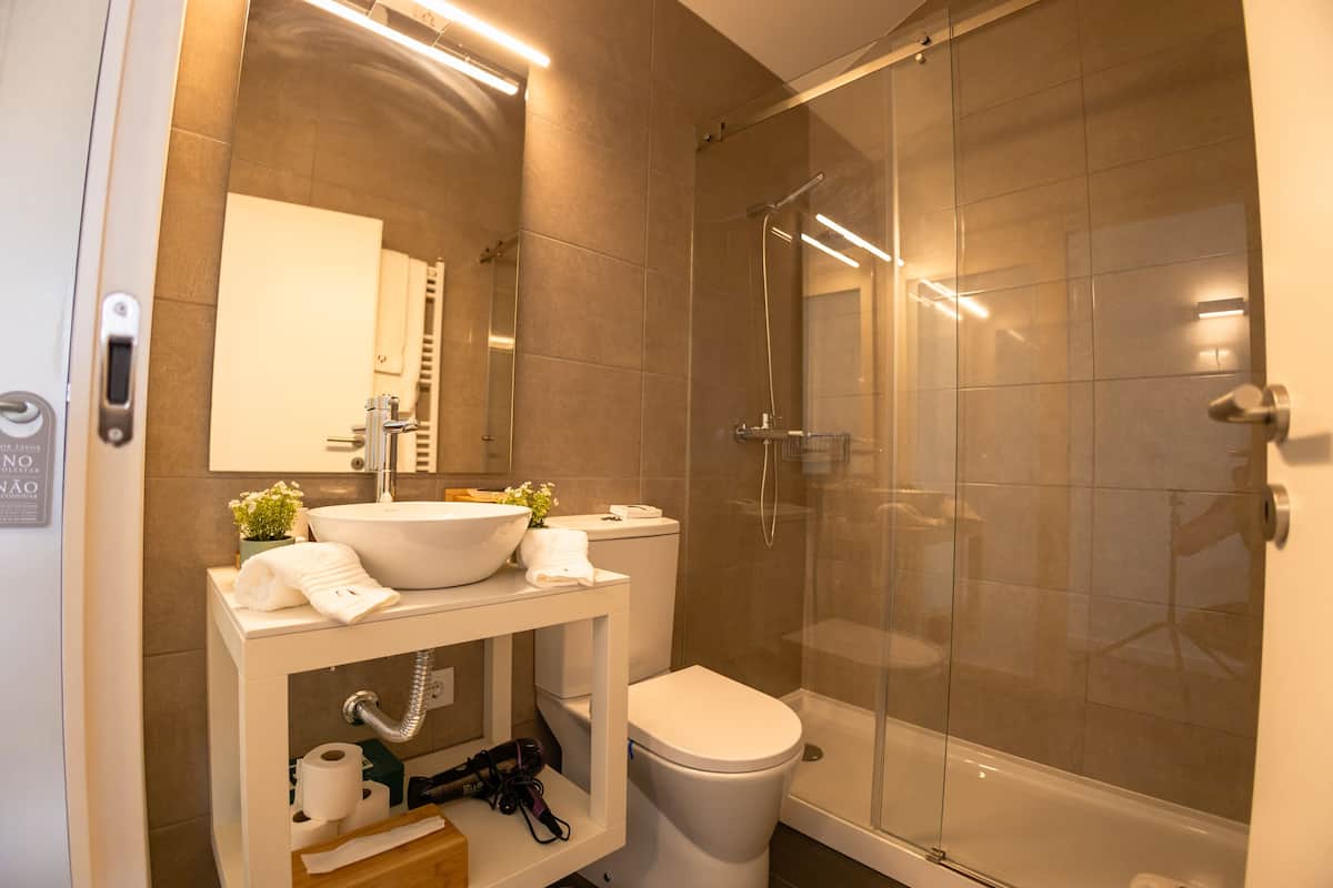 Um banheiro moderno com chuveiro em box de vidro, pia branca e vaso sanitário.