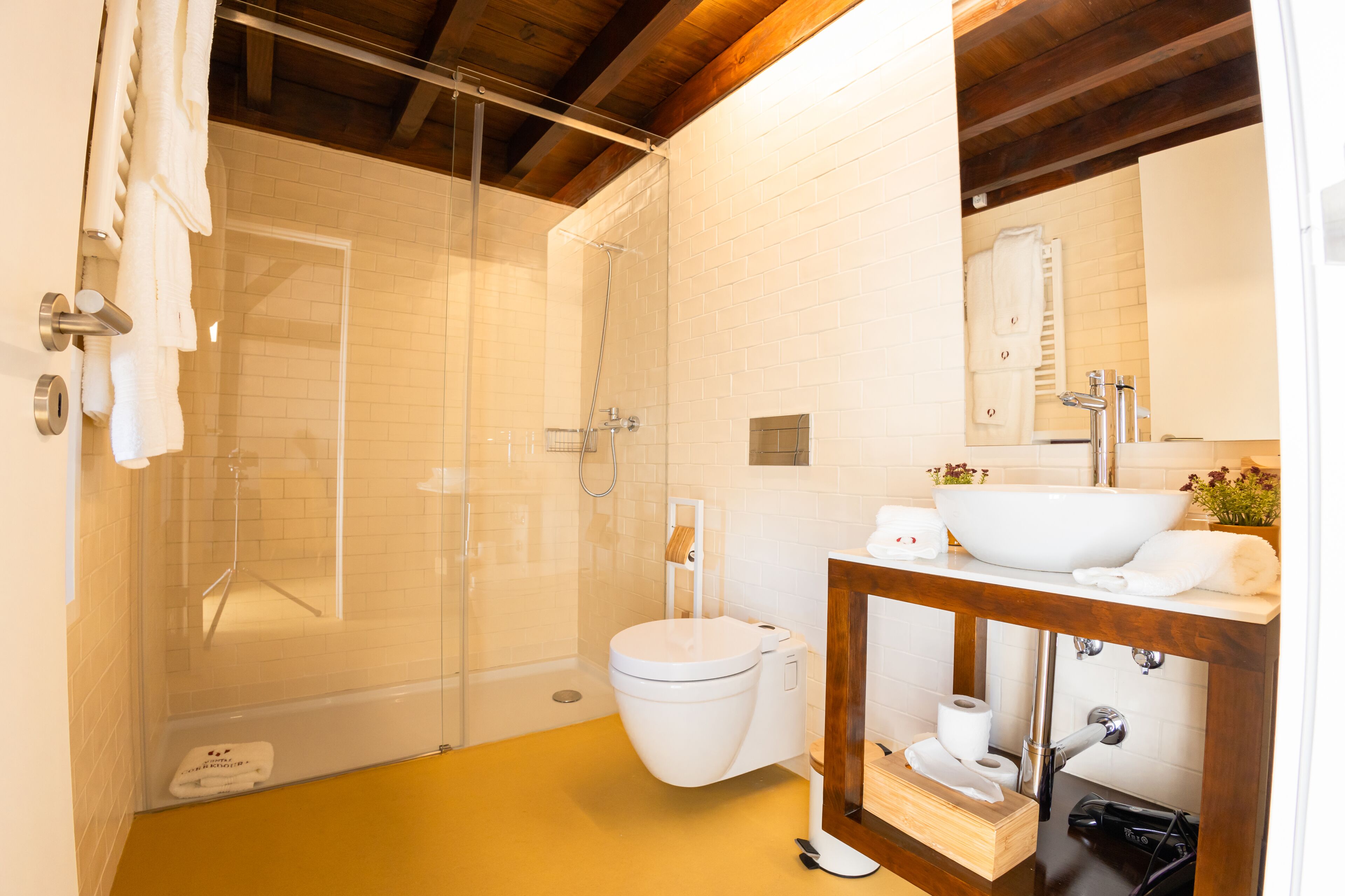 A modern bathroom with a glass-enclosed shower, a white toilet, and a wooden vanity with a sink.