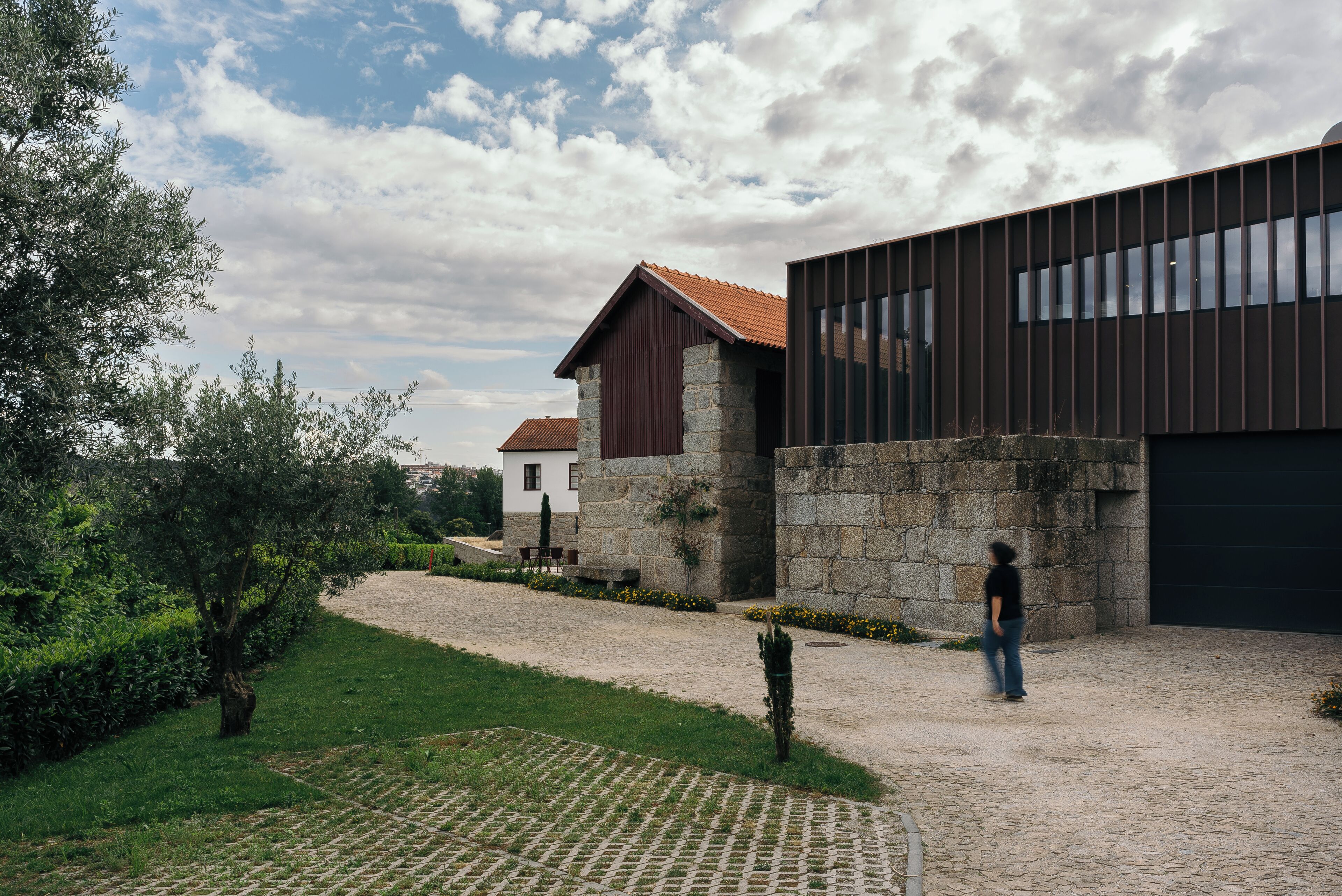 A modern building with a stone facade and a wooden structure with a red roof.