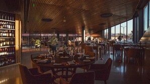 A restaurant with a wooden ceiling, large windows, and a bar area with wine bottles. - Quinta da Corredoura Hotel Rural (Guimarães)