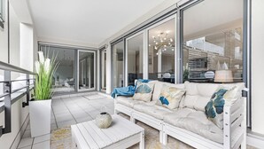 Un salon moderne avec un canapé blanc, une table basse et une grande fenêtre donnant sur l’intérieur.
