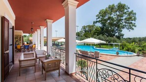 A covered outdoor area with a pool, seating, and a view of the surrounding landscape.