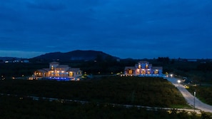 Two large, illuminated buildings with a swimming pool in front, surrounded by hills. - Aneli Villas - Villa Semeli (Zakynthos)