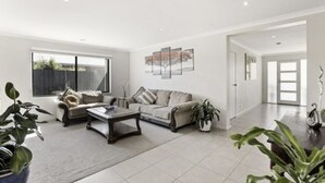 A spacious living room with a sofa, coffee table, and potted plants.