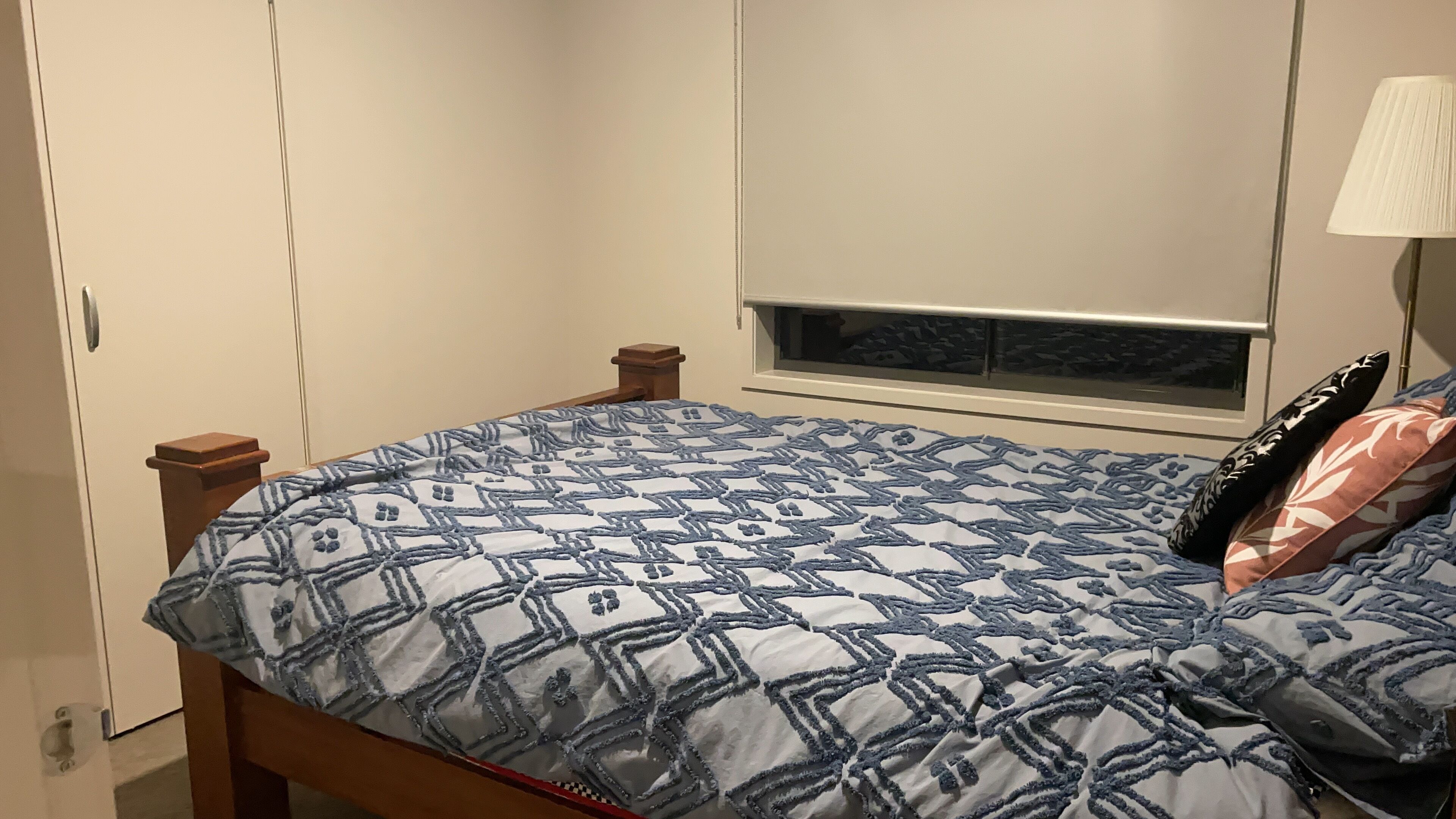 A bedroom with a bed, a window, and a wardrobe.