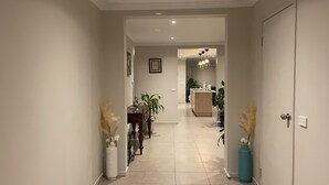 A hallway with a dining area, kitchen, and a door leading to another room.
