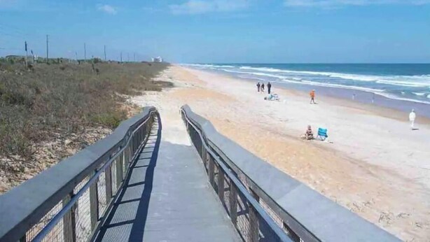 Ein Strand mit einer Betonpromenade, die zum Ufer führt.