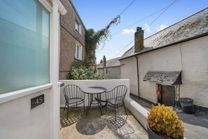A small outdoor patio with a table and two chairs, a potted plant, and a building number '45'.