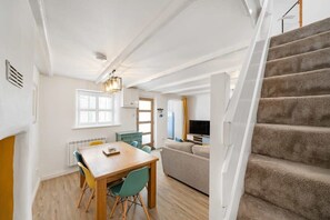 A modern interior with a dining area, sofa, TV, and staircase. - Beautiful Cottage Minutes from Mevagissey Harbour (Saint Austell)