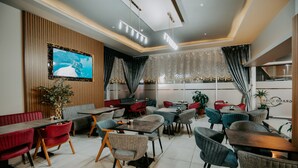 Un restaurant modern amb diverses zones d'ambientació, incloent seients privades i taules, i un gran televisor penjat a la paret.
