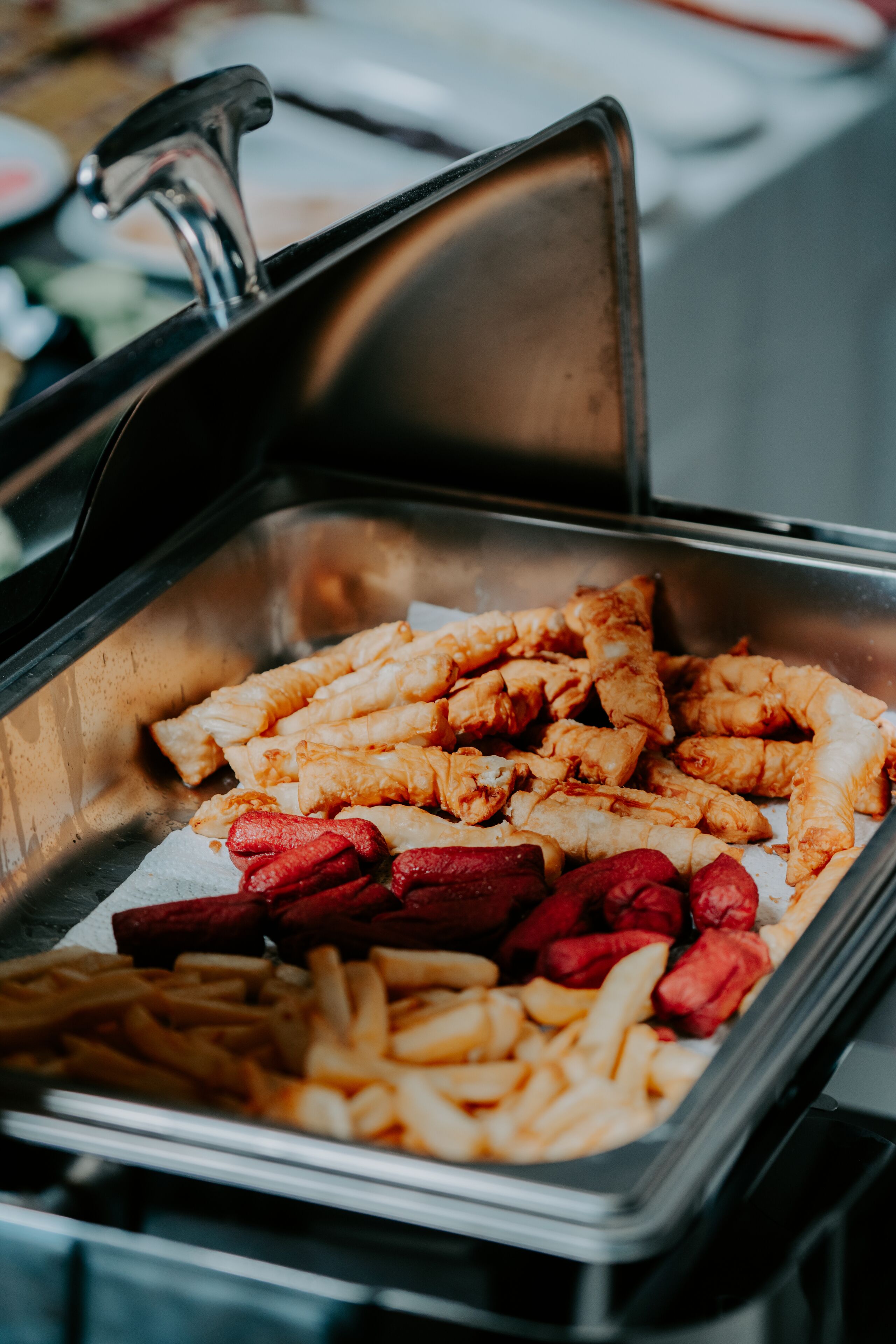 A buffet with various food items including fried chicken, French fries, and red meat.