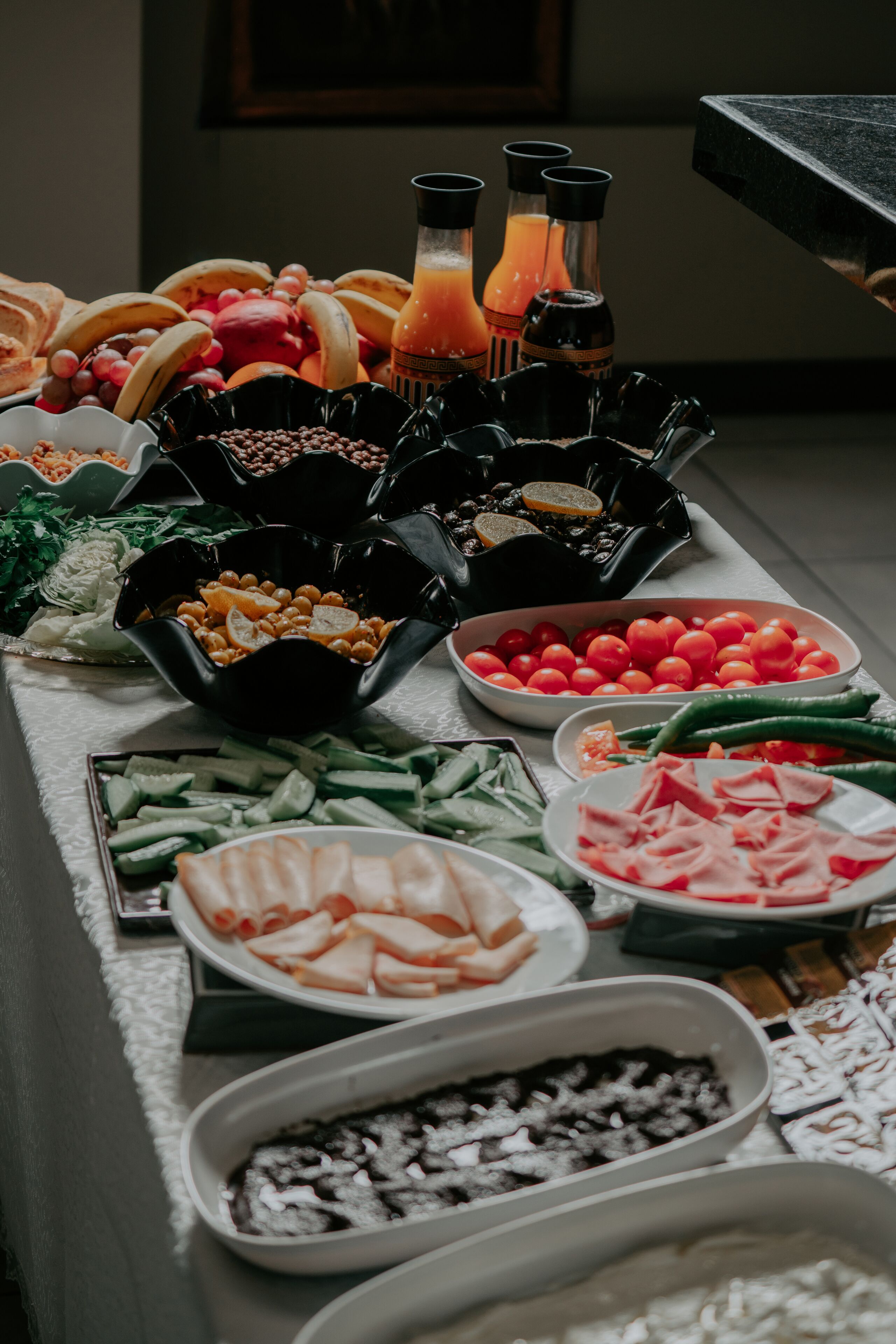 A buffet table with various food items including fruits, vegetables, and meats.