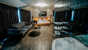 Una habitació d'hotel moderna amb un llit gran, un sofà, una taula de cafè i una banyera.
